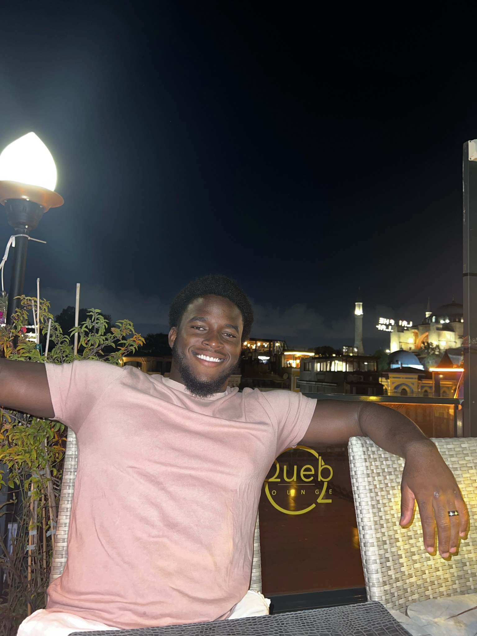 Olufemi smiling at an outdoor restaurant in the evening