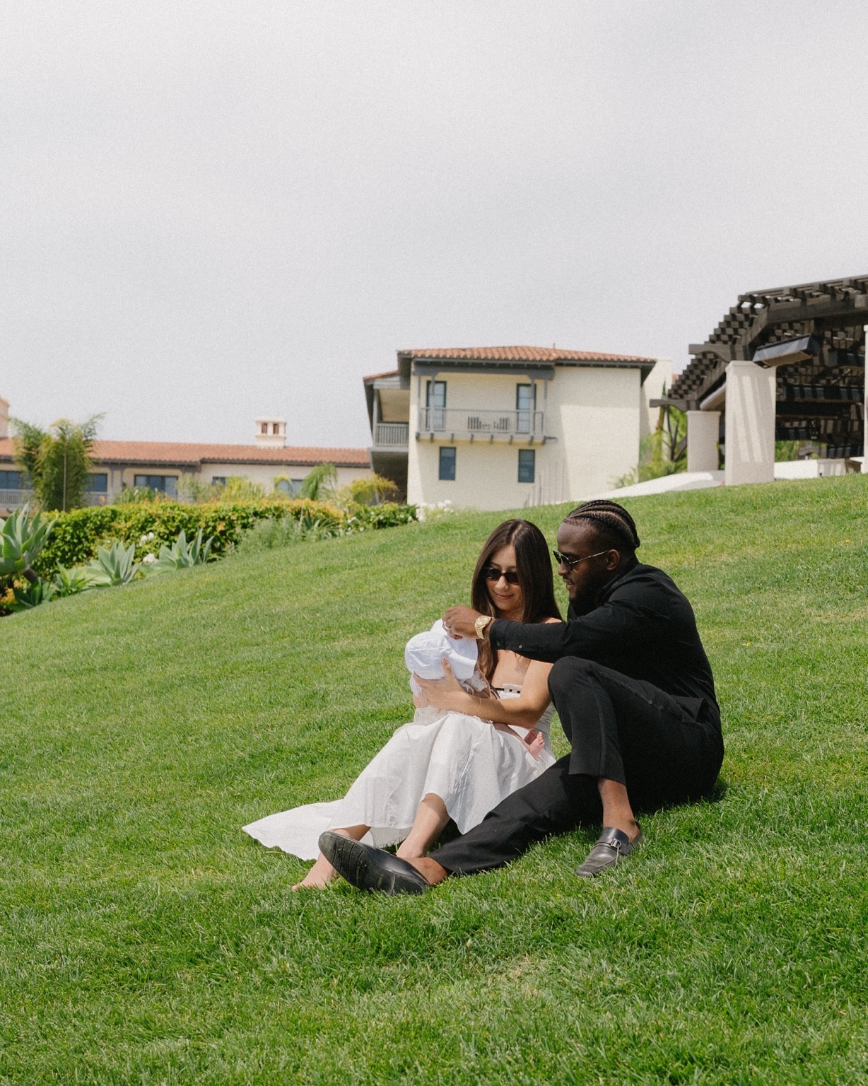 Olufemi with his wife and baby, sitting together on the grass